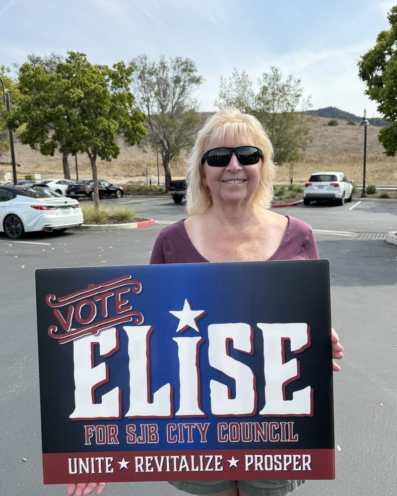 A supporter holding a Vote Elise for SJB City Council sign outdoors