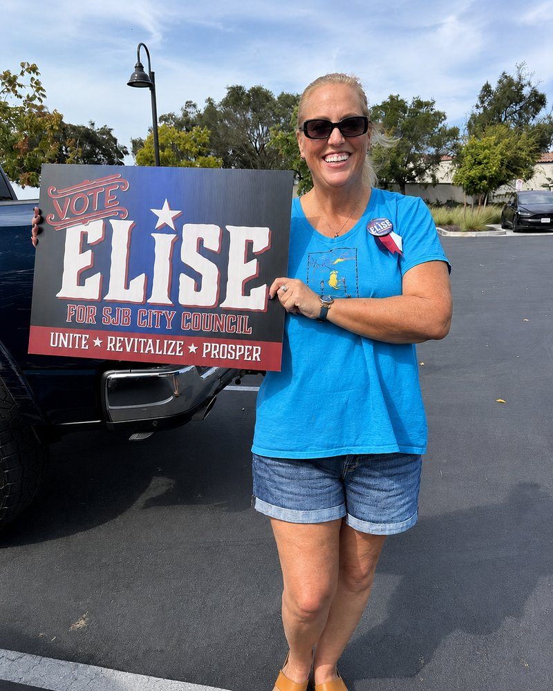 Elise Brentnall wearing a Vote Elise button and holding a Vote Elise for SJB City Council yard sign