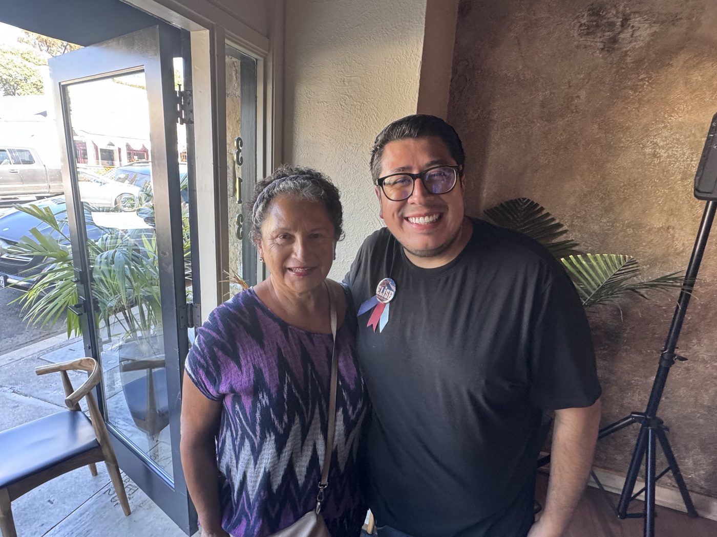 Two supporters at the door of the launch party, one wearing a Vote Elise button