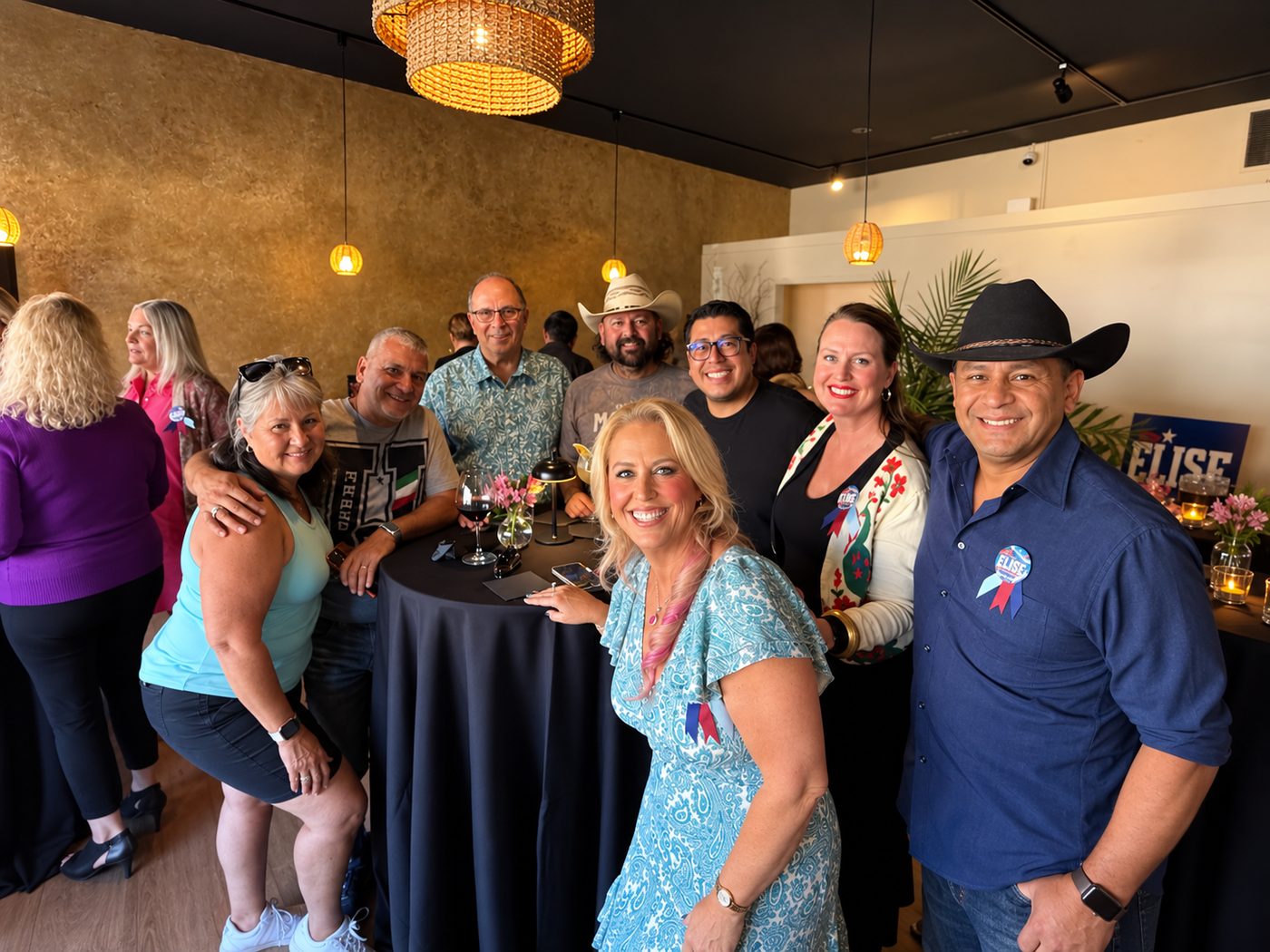 A group of supporters gathered around a table at the launch party, several wearing Vote Elise buttons